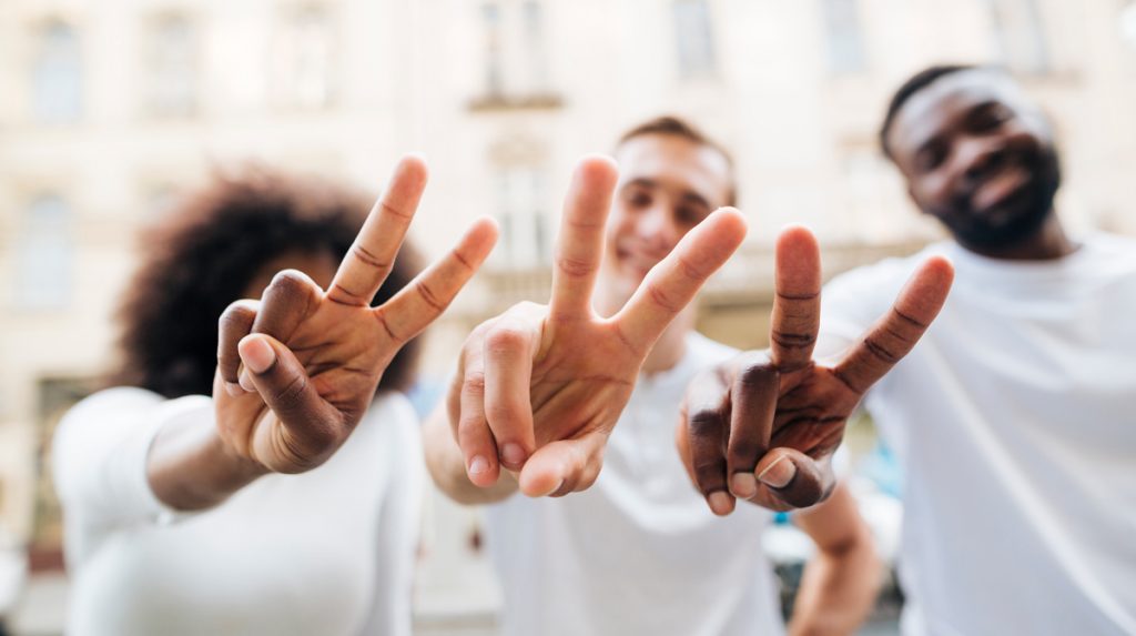 Intercultural friends showing peace sign.