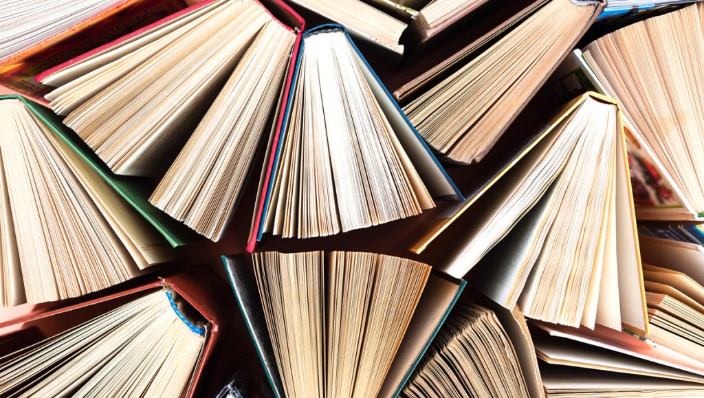 Old and used hardback books or text books seen from above. Books and reading are essential for self improvement, gaining knowledge and success in our careers, business and personal lives.