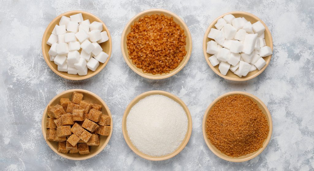 Various types of sugar, brown sugar and white on concrete ,top view.