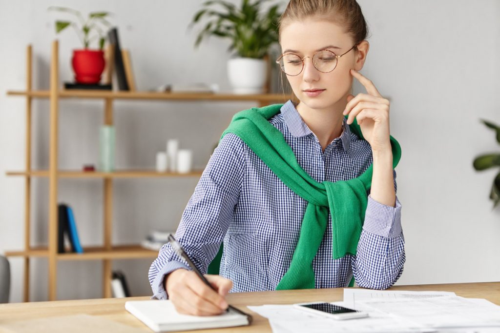 Elegant businesswoman dressed formally and writing essay.