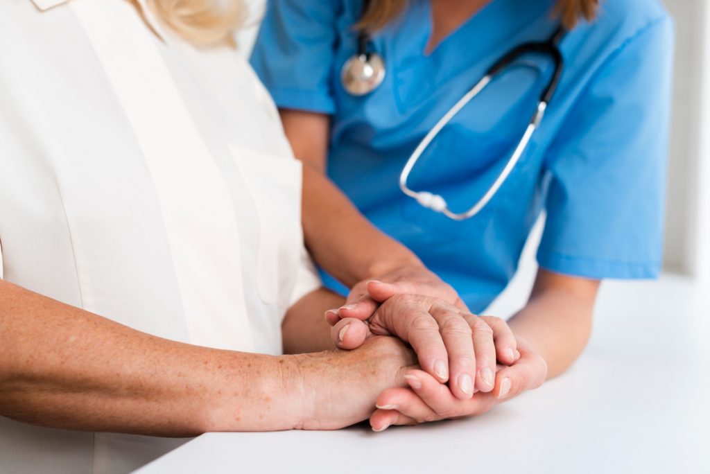 Doctor and old woman holding hands close-up.