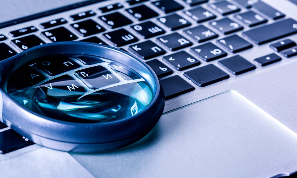 Closeup images of magnifying glass on laptop keyboard.