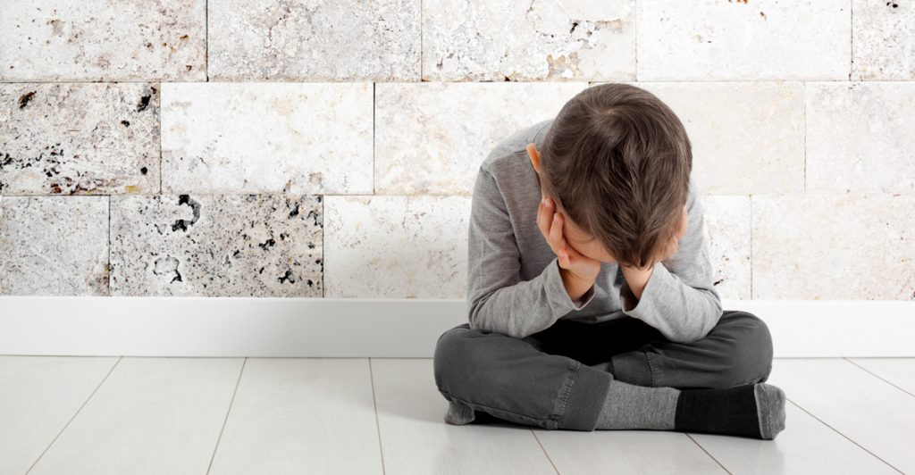 A child whose depression is sitting on the floor.