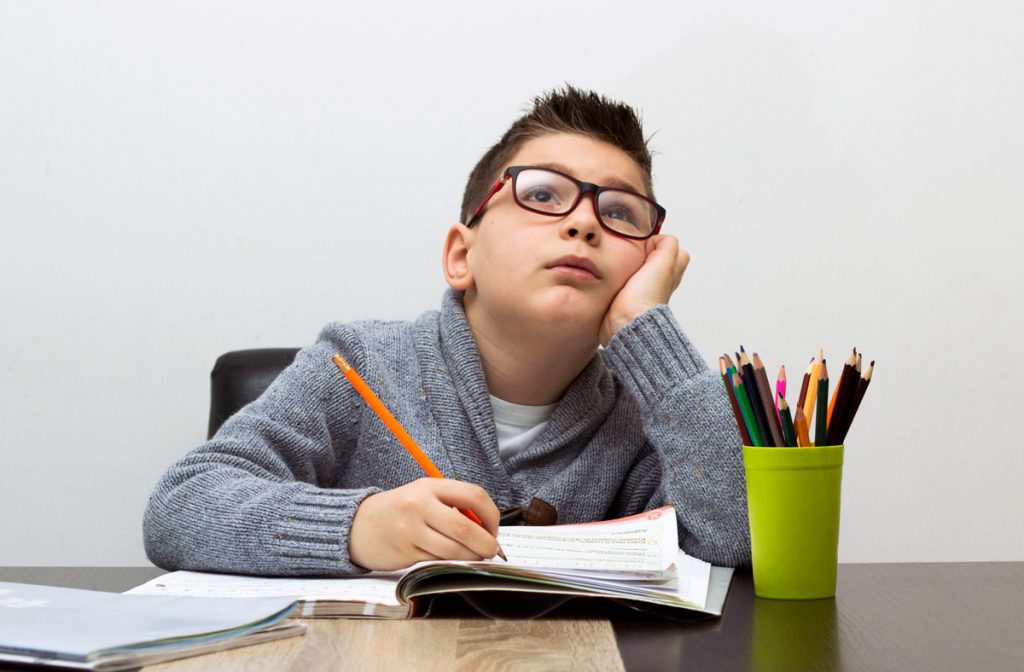 Young boy frustrated over homework, writing at home.