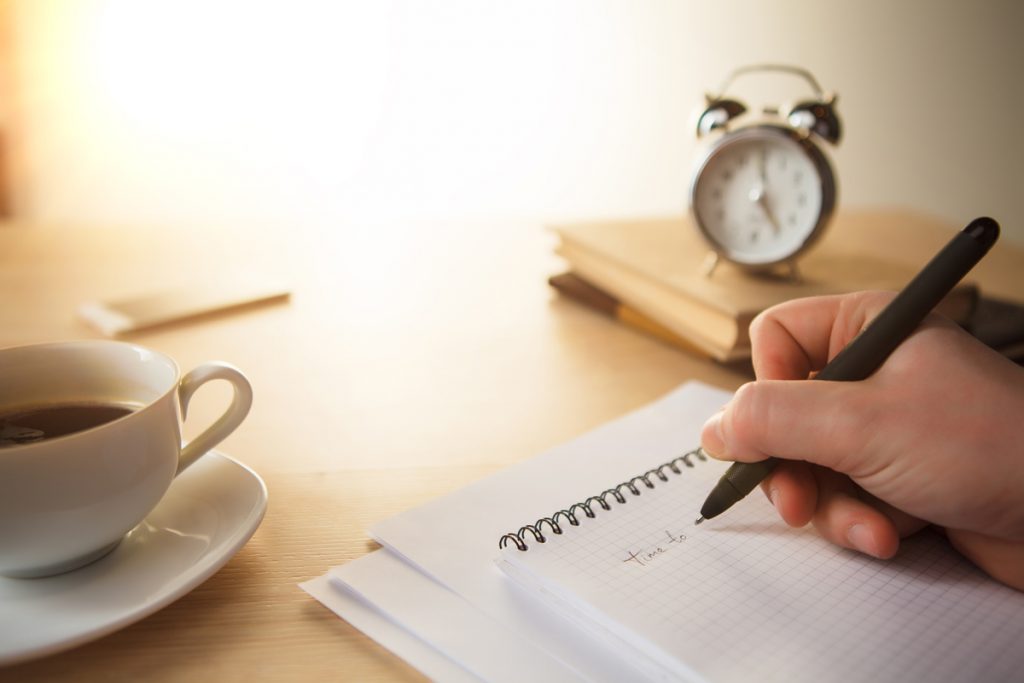 The male hand with a pen and the service hours and notebook on the table.